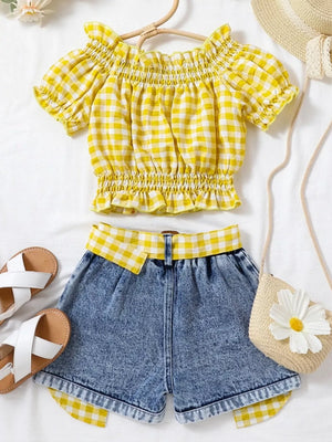 Yellow gingham off-shoulder top with smocked bodice and denim shorts with gingham trim.