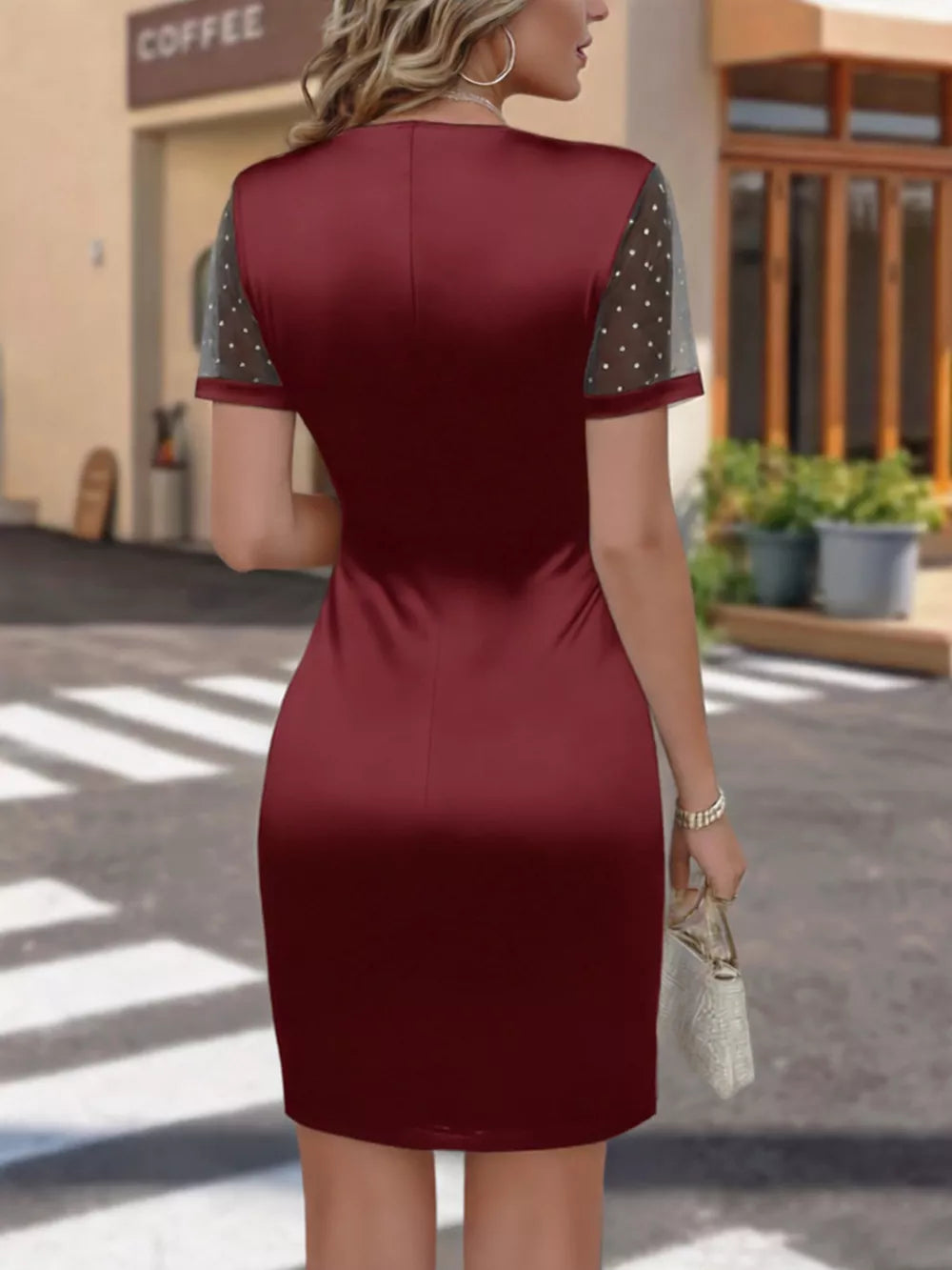 Wine red satin dress with ruched detail and sheer polka dot sleeves.