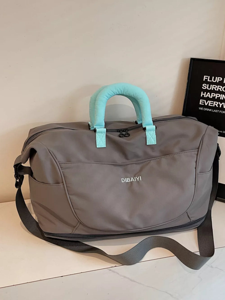 Spacious gray Oxford cloth travel duffel bag with light blue padded handles and shoulder strap.