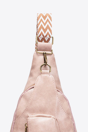 Pink textured sling bag with woven zig-zag strap detail and gold hardware.