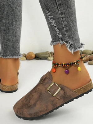 Brown textured suede mules with buckle detail and cork sole.