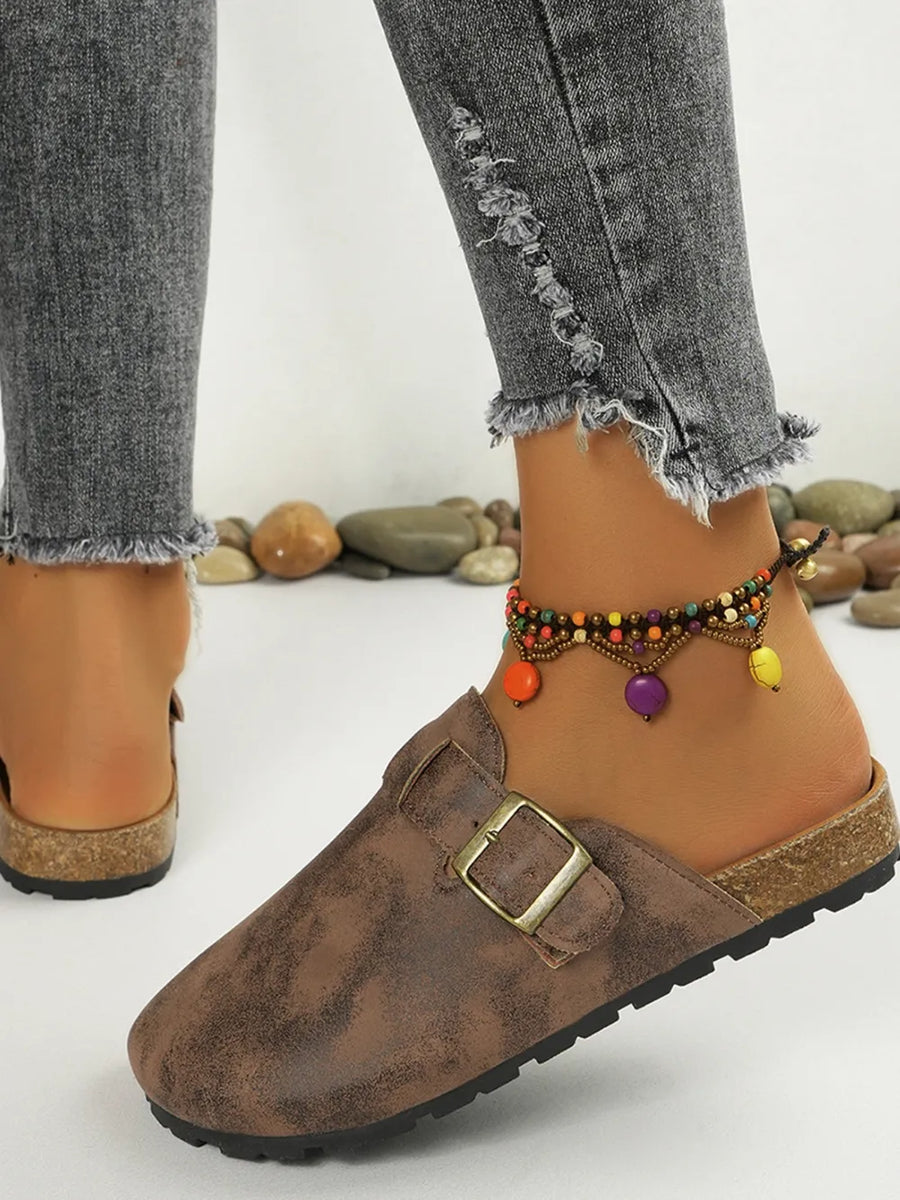 Brown textured suede mules with buckle detail and cork sole.