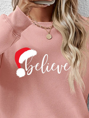 Blush pink raglan sweatshirt with "Believe" graphic and Santa hat detail