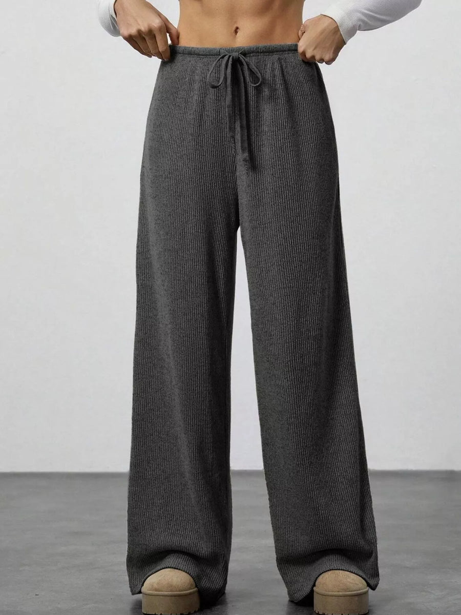 Dark gray ribbed wide-leg pants with drawstring waist and pockets.