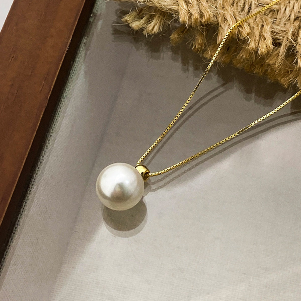 Gold chain necklace with a single elegant pearl pendant.