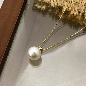Gold chain necklace with a single elegant pearl pendant.