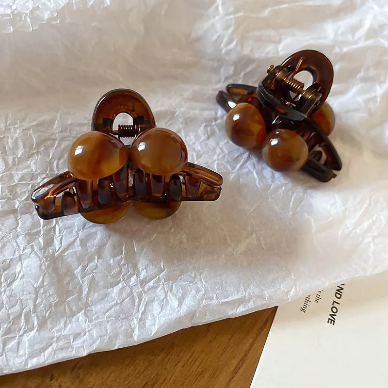 Brown resin orb hair claws with acrylic material and a casual style.