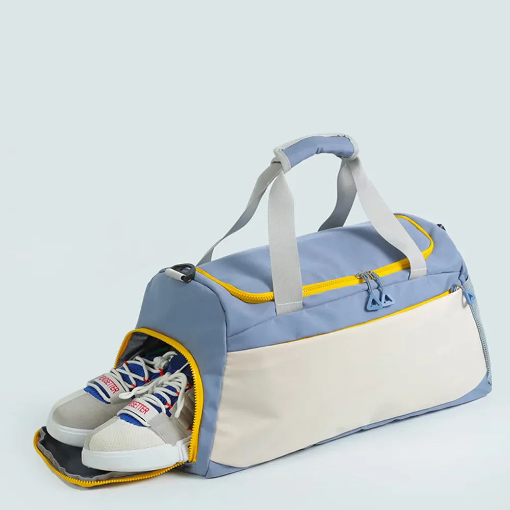 Colorblock duffel bag in dusty blue and beige with yellow trim, featuring a shoe compartment with sneakers.