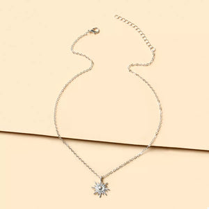 Silver sunburst pendant necklace with delicate chain and lace trim detail.