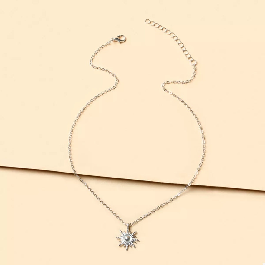 Silver sunburst pendant necklace with delicate chain and lace trim detail.
