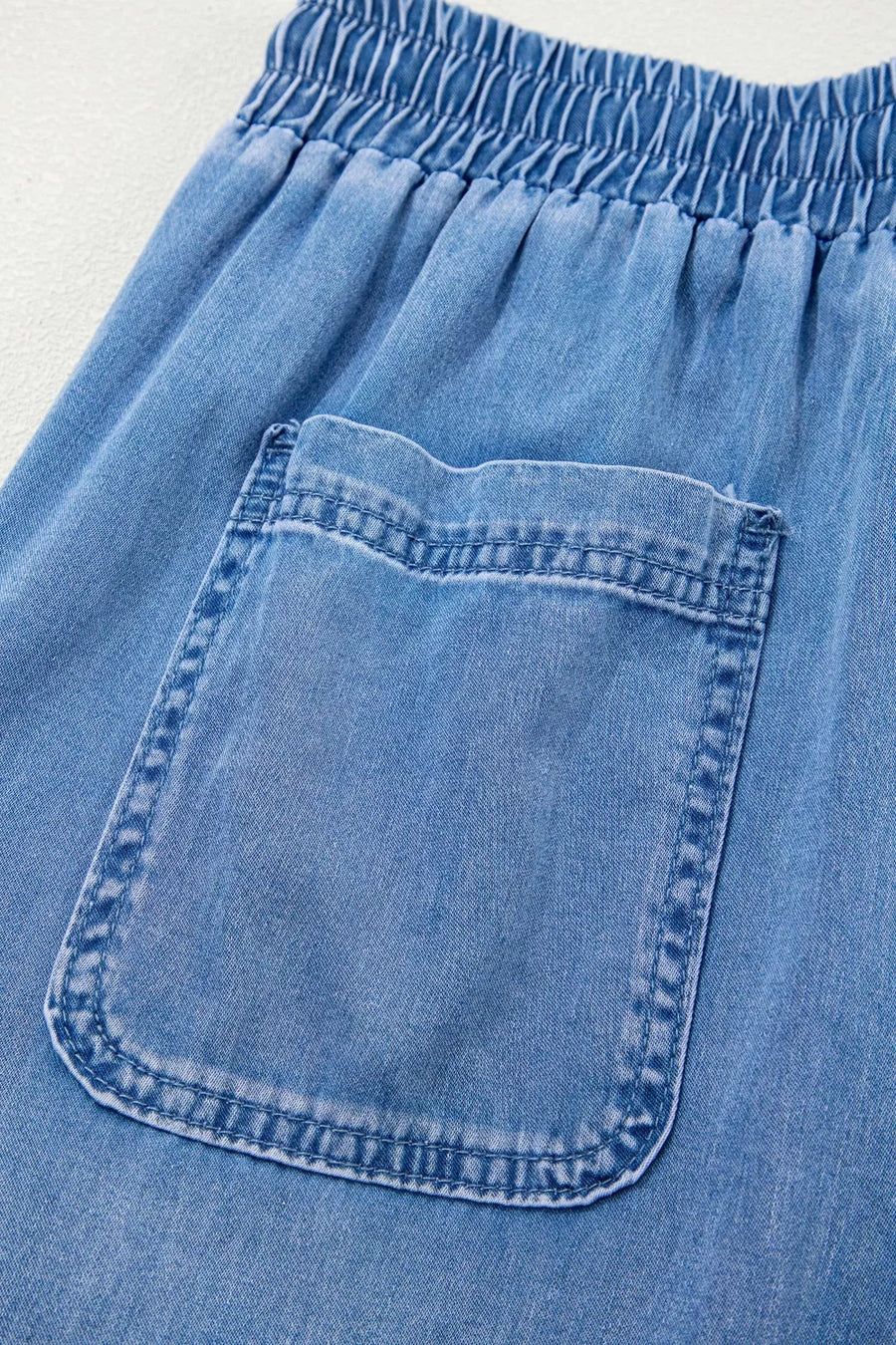 Relaxed light blue denim maternity jeans with drawstring waist and cargo pocket detail.