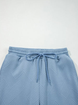 Light blue textured drawstring shorts with a geometric pattern and elastic waistband.