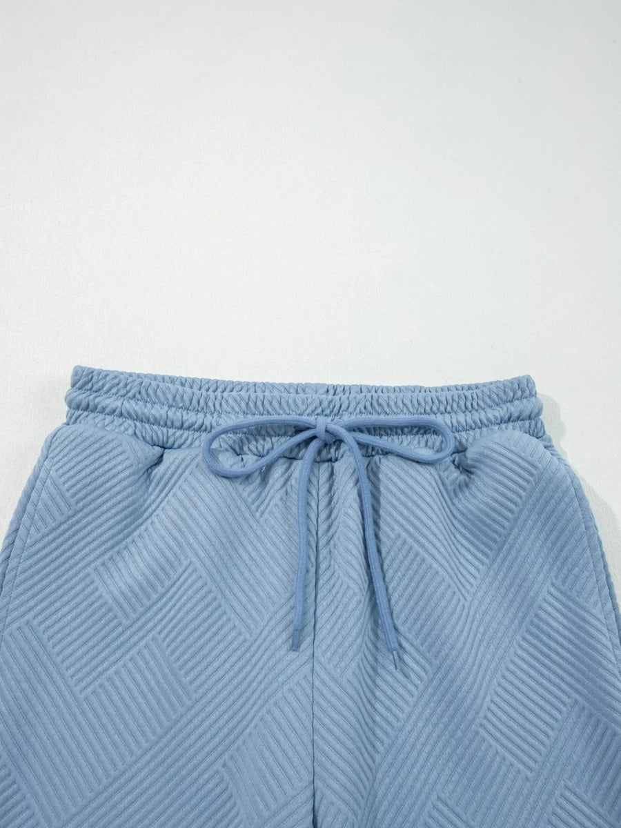 Light blue textured drawstring shorts with a geometric pattern and elastic waistband.