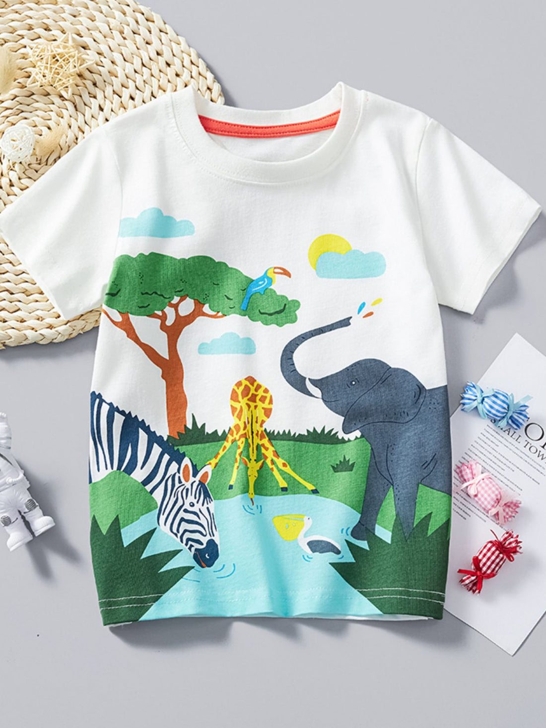 White cotton crew neck t-shirt with safari animal print featuring elephant, giraffe, zebra, toucan, and pelican.