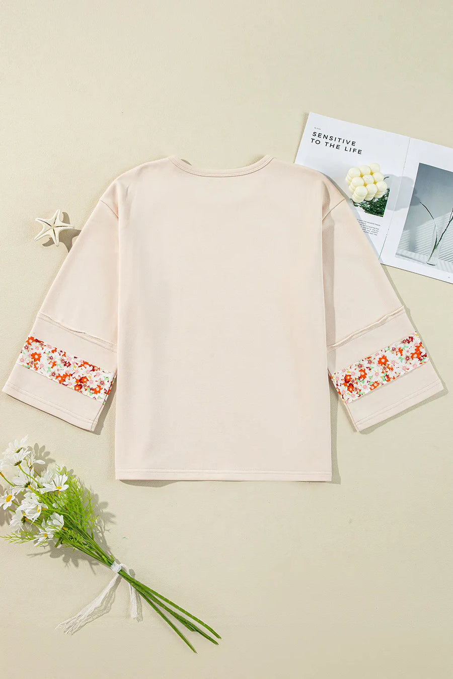 Ivory sweatshirt with floral appliqué raglan sleeves and crew neck.