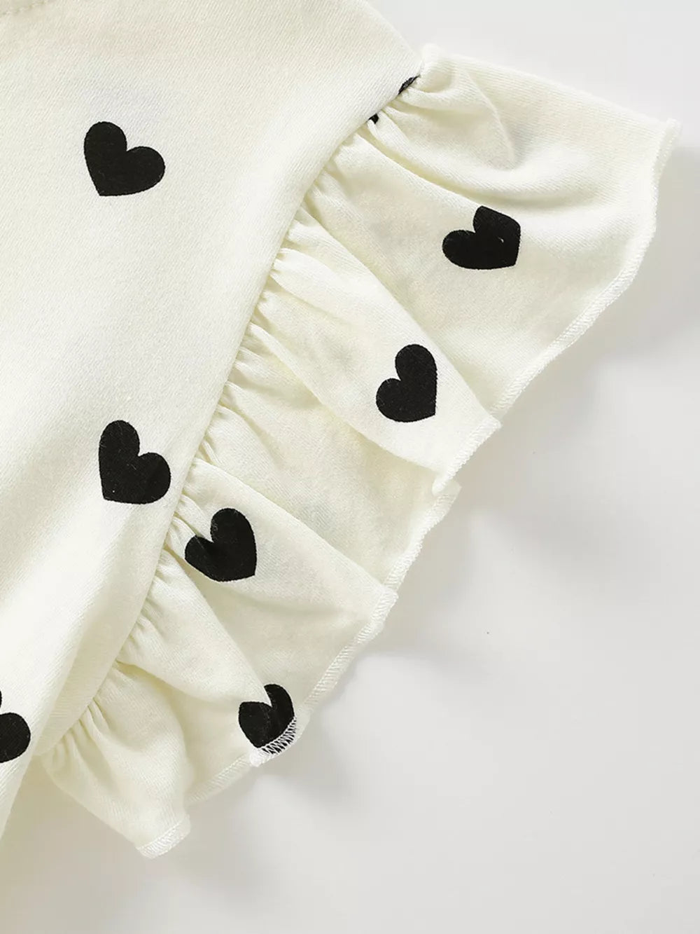 Children's white dress with black heart print and ruffle sleeves.