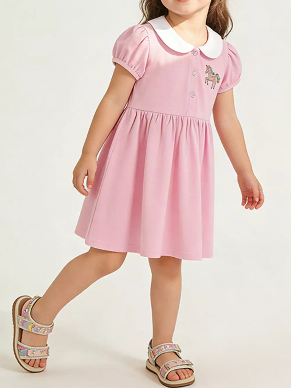 Pink cotton toddler dress with puff sleeves, Peter Pan collar, and unicorn embroidery.