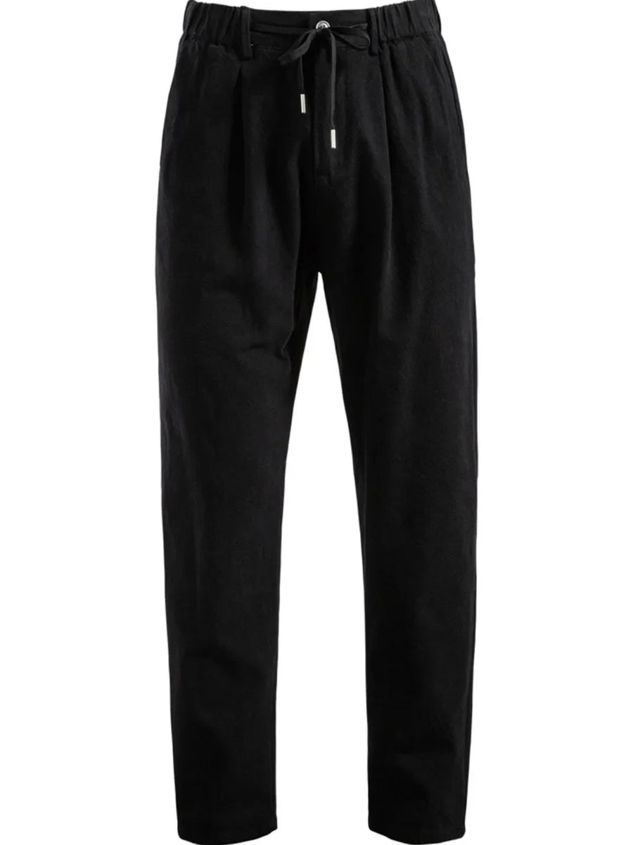 Black pleated linen drawstring trousers with a relaxed fit.