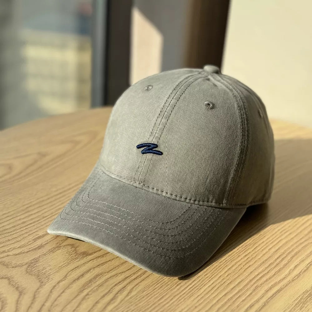 Distressed dark gray cotton baseball hat with curved brim and navy embroidered logo.