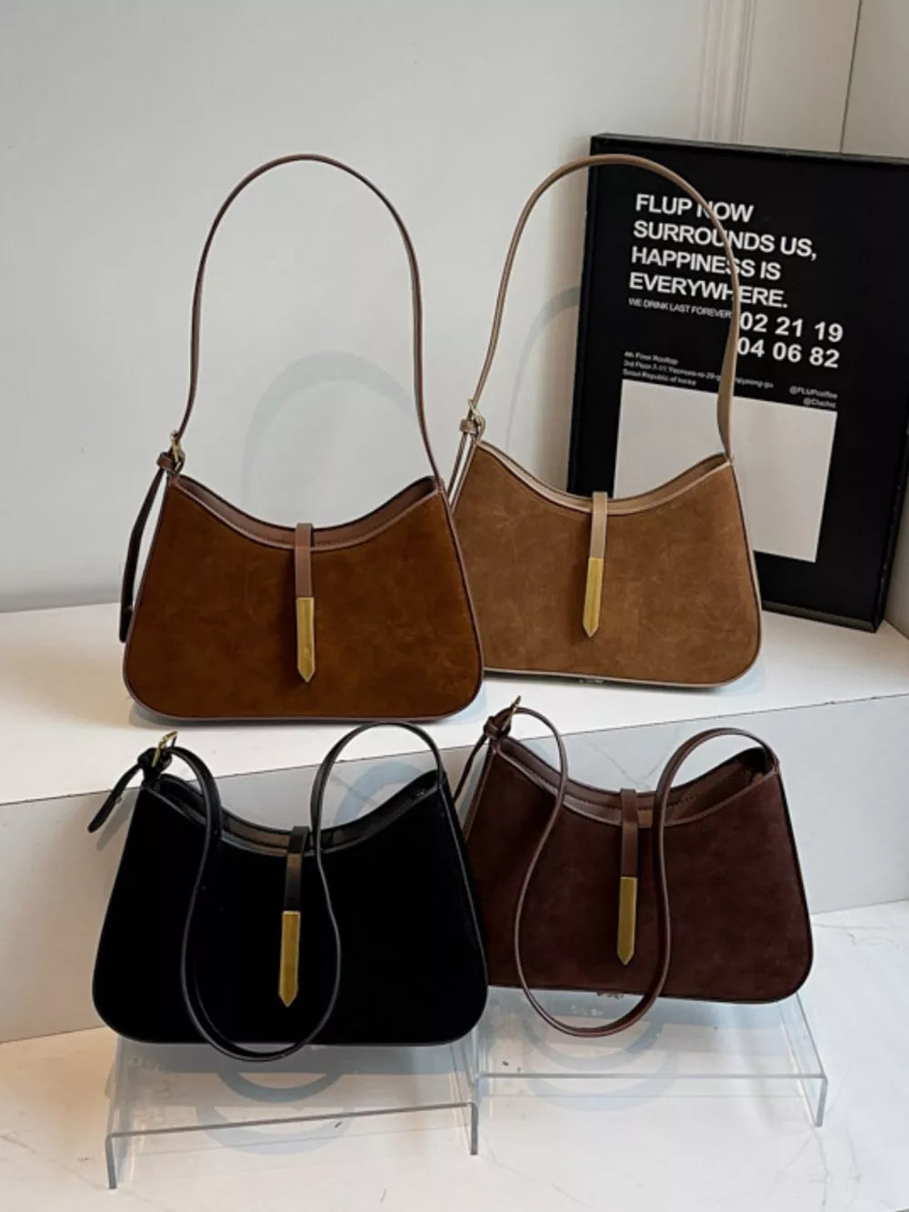 Curved suede and leather shoulder bags in coffee brown and black with adjustable straps and gold hardware.