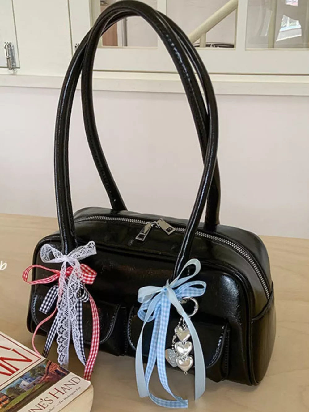 Black patent shoulder bag with ribbon embellishments and heart charms