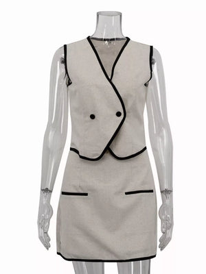 Sleeveless beige mini dress with black trim and double-breasted vest detail