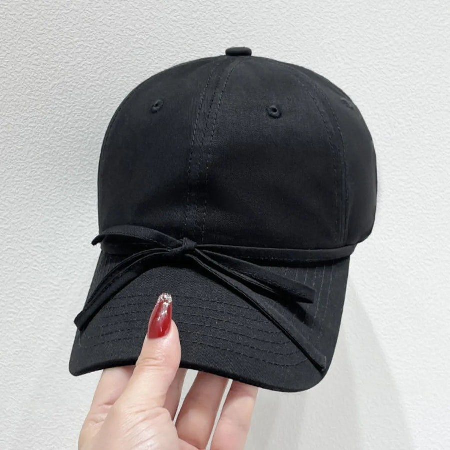 Black baseball cap with a decorative bow detail on the brim.