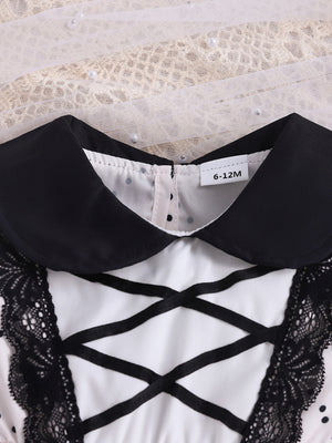 Baby dress with black collar, lace trim, criss-cross ribbon detail, and polka dot pattern.