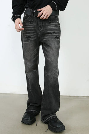 Distressed flare jeans in washed black denim with ripped details and a raw hem.