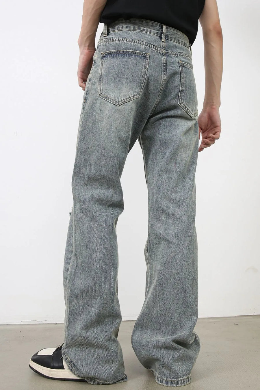 Distressed flare jeans in medium wash denim with raw-cut knee details.