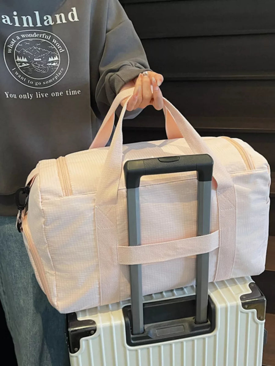 Pink textured duffel bag with light pink straps and zipper details.