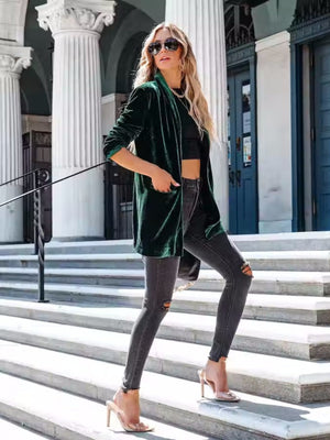 Dark green velvet blazer with a drape front and open closure, worn by a model.