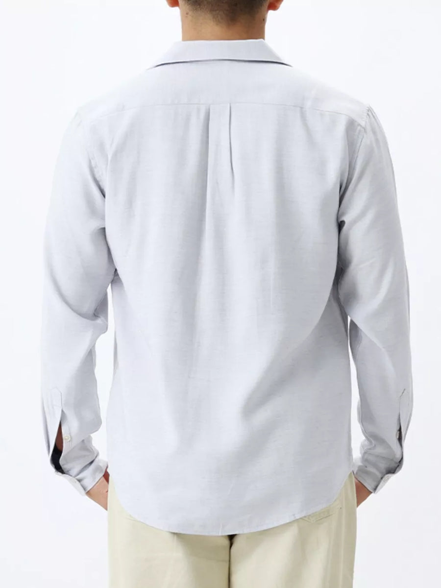 Relaxed camp collar button-up shirt in light blue with back pleats and buttoned cuffs.