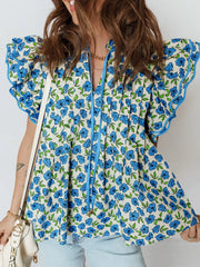 Floral ruffle sleeve tie-neck blouse with blue flowers and green leaves on a cream cotton fabric.