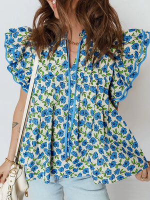 Floral ruffle sleeve tie-neck blouse with blue flowers and green leaves on a cream cotton fabric.