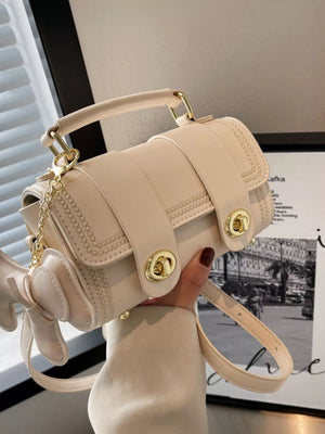 Beige PU leather crossbody bag with decorative stitching and bow charm.