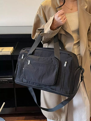 Black canvas duffel bag with multiple zippered pockets and adjustable strap