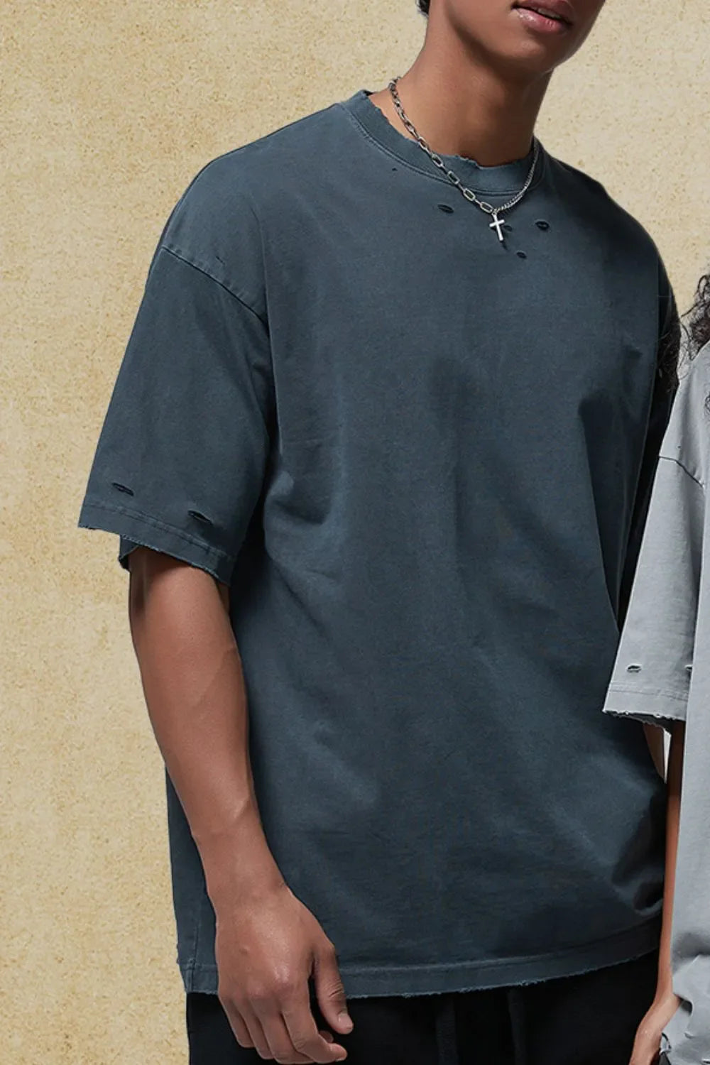Distressed oversized cotton tee in dark gray with ripped details and raw hem.