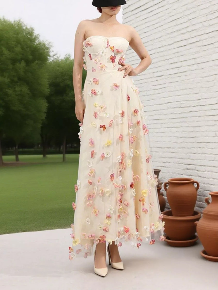 Strapless ivory tulle maxi dress with floral appliques, sweetheart neckline, and flowing skirt.