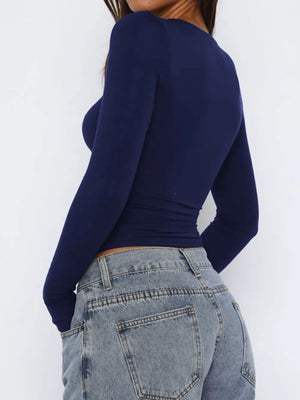 Navy long sleeve ruched crop top with a crew neck, styled with denim jeans.