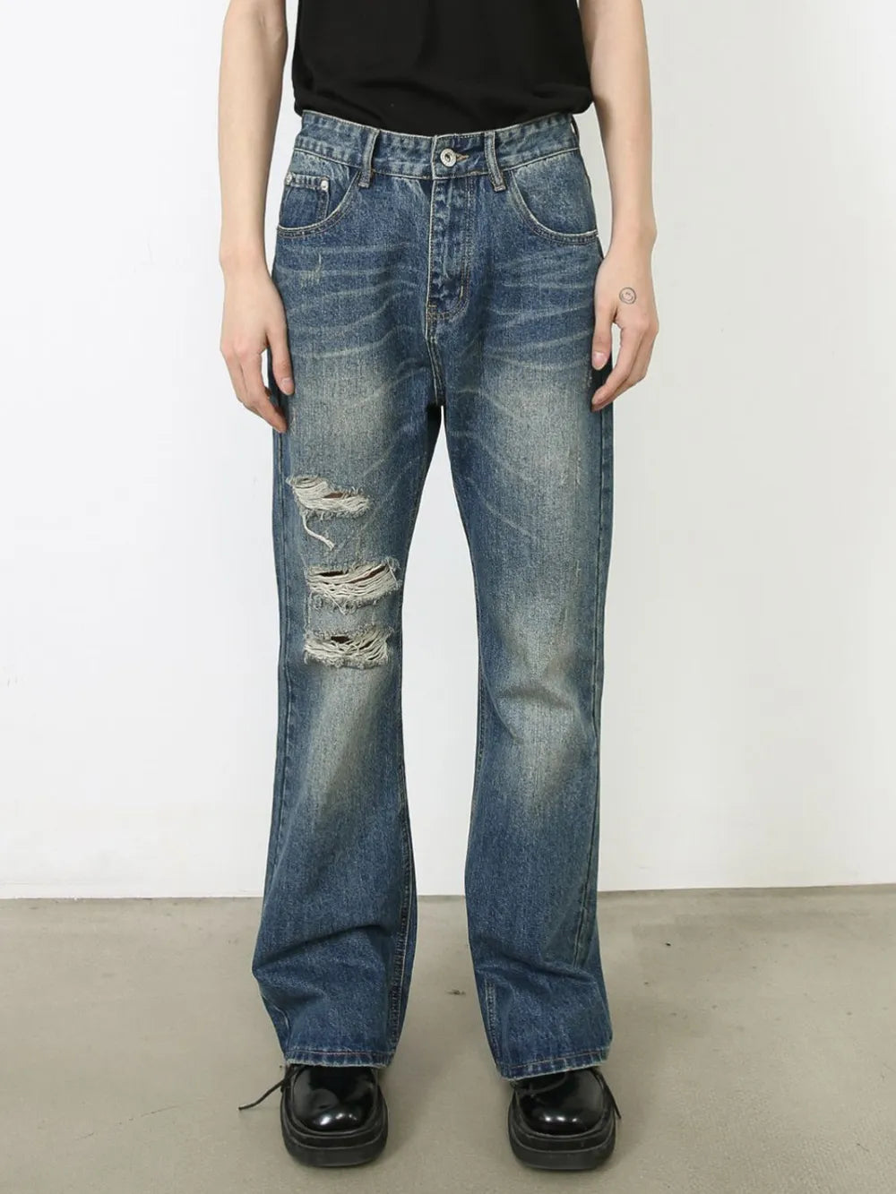 Distressed flare leg jeans in medium wash denim with ripped details.