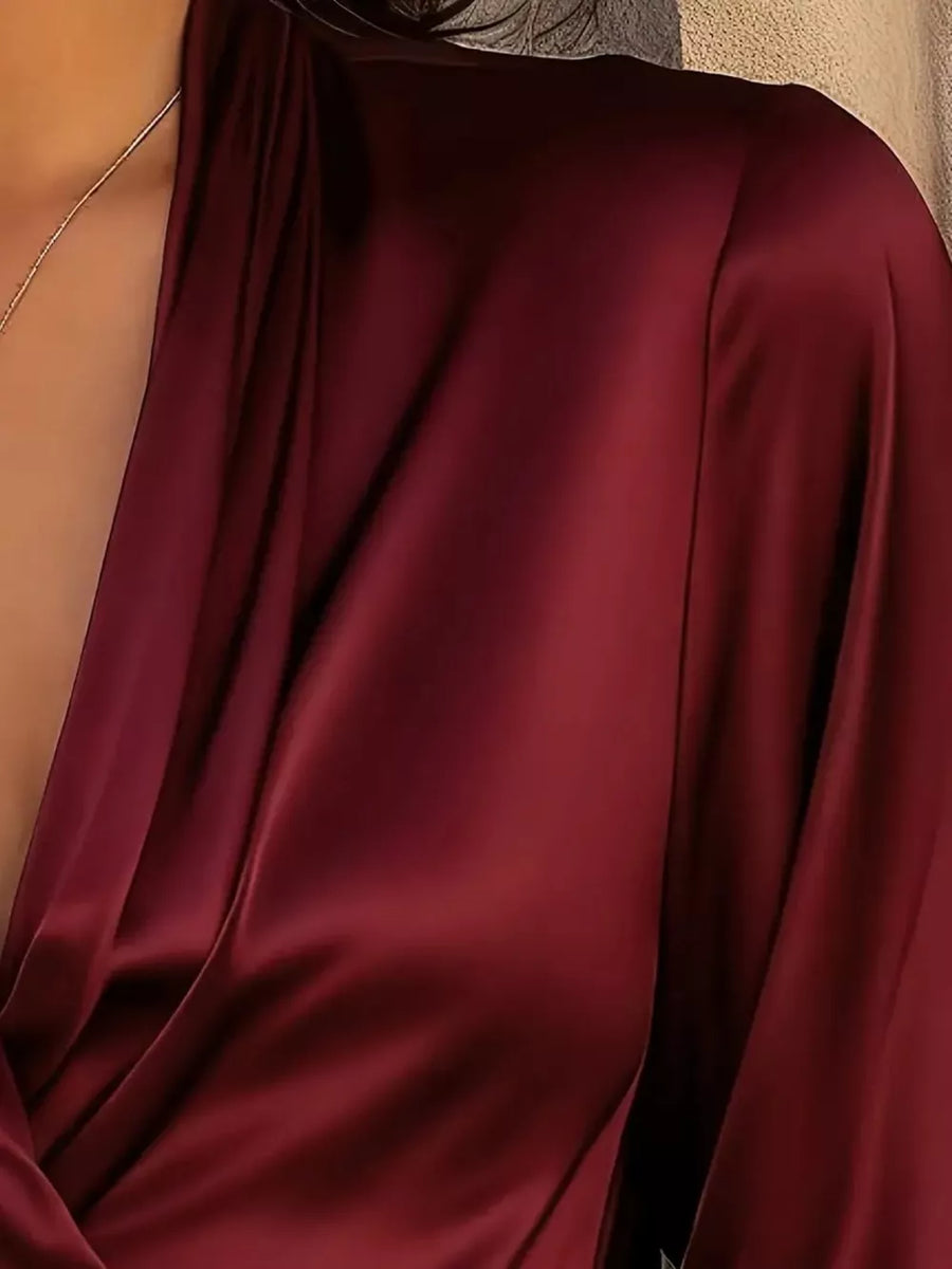 Elegant satin surplice blouse in wine red with draped neckline detail.