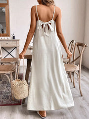 Maxi dress with adjustable spaghetti straps and a back bow detail in a light neutral color.