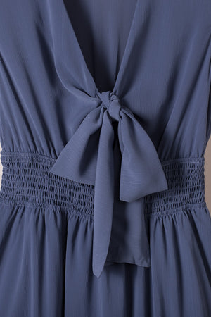 Dusty blue mini dress with V-neck, ruffled bow tie, and smocked waist.