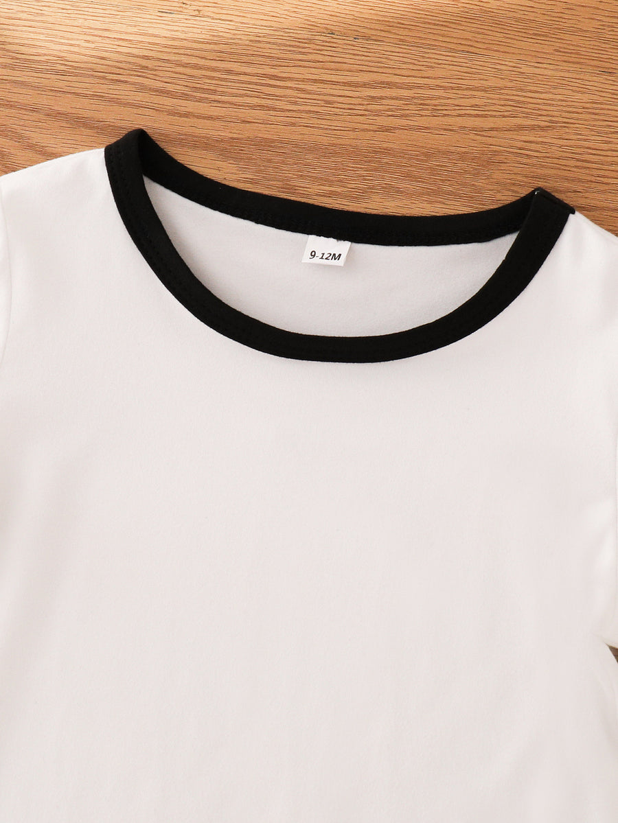 White baby outfit with black trim neckline and size tag