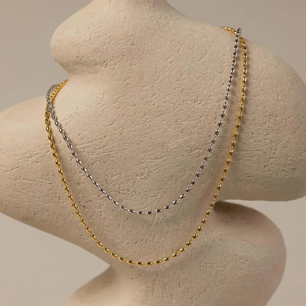 Dual-tone capsule chain necklace in gold and silver with bead detailing.