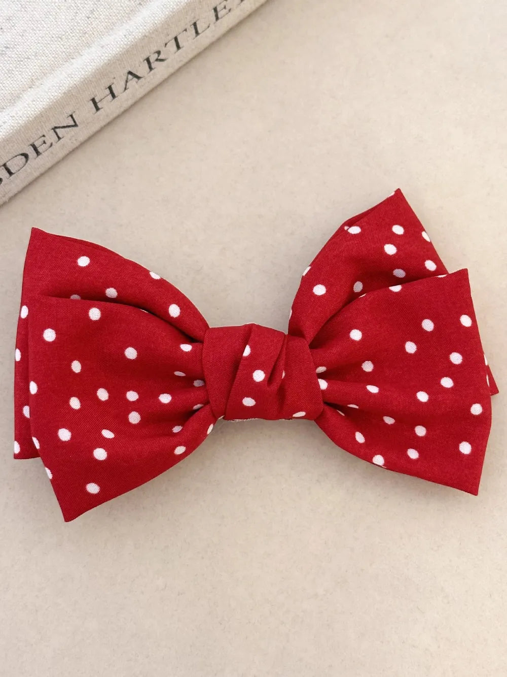 Deep red polka dot bow hair clip with a knotted center detail.