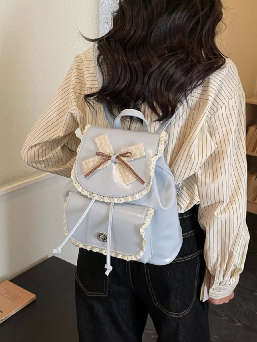 Blue mini backpack with lace trim and a bow detail, featuring front pockets.