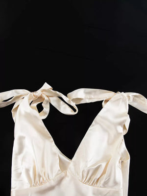 Cream satin halter top with tie straps and a deep V-neck.