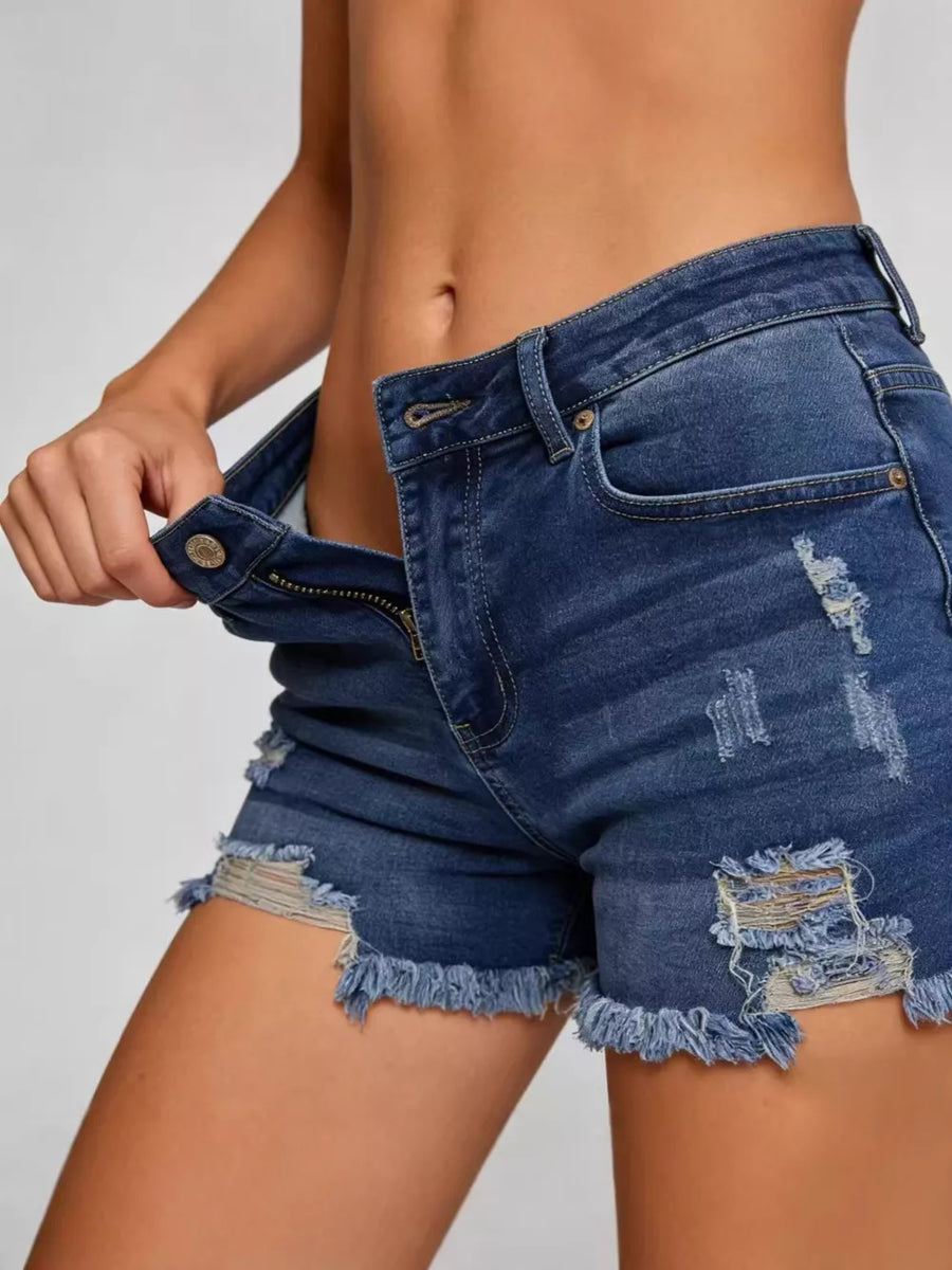 Distressed dark blue denim shorts with raw frayed hem and button fly.